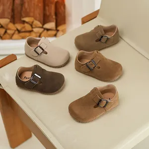 A collection of toddler buckled suede loafers in earth tones displayed on a vintage chair