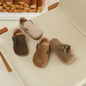 Detailed view of children's suede Birkenstock-style shoes in various earth tones on a chair