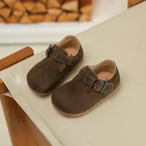 Detail shot of brown suede children's casual shoes with a metallic buckle strap