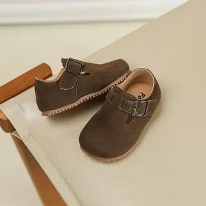 Close-up of brown suede children's loafers with adjustable buckle strap and sole
