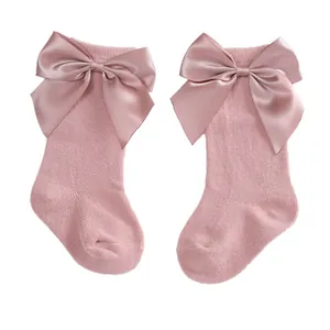 Adorable pink baby knee-high socks featuring large decorative satin bows for little girls