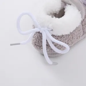 Close-up detail of soft white fleece lining and drawstring bow on a grey baby bootie