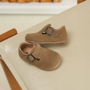 Close-up of brown suede children's buckle shoes on a beige leather background