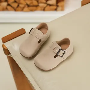 Detailed top-down view of beige children's suede T-strap shoes with metal buckle