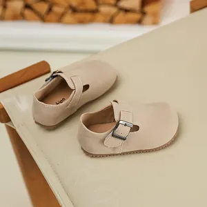 Detail of beige suede children's Mary Jane shoes with metal buckle strap