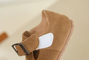 Detailed view of the brown suede children's shoes with velcro strap and metal buckle