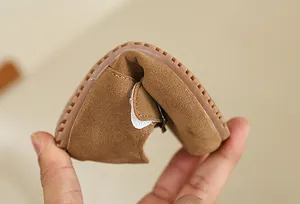 Detail view of flexible brown suede baby shoes showing the soft sole bending feature