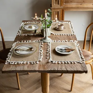 Natural rustic farmhouse jute placemats with white tassel fringe on a wooden dining table.