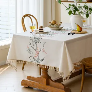 Detailed view of cream embroidered floral tablecloth with elegant tassel fringe accents