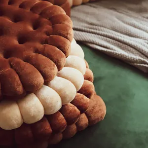 Close-up detail of soft biscuit-shaped plush cushions stacked in brown and cream colors