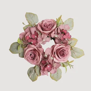 Vista superior de una corona de flores artificiales rosa empolvado con hojas realistas