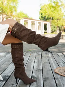 Side view detail of brown suede slouchy stiletto knee-high boots with buckle strap