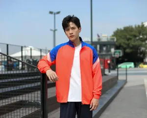 Homme portant une veste de sport bicolore orange et bleu dans un cadre extérieur