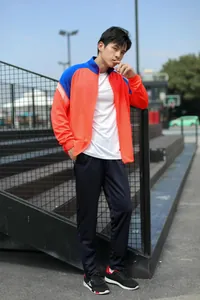 Vue en pied d'un mannequin en survêtement de sport orange et bleu vif à l'extérieur