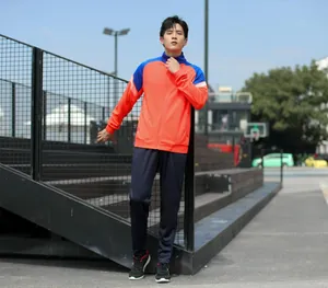 Vue en pied d'un mannequin portant un ensemble de survêtement de sport orange et bleu