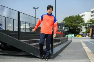 Photo d'un homme portant un survêtement de sport orange et bleu en extérieur