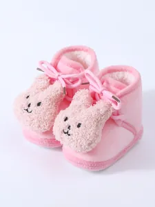 Close-up detail of soft pink infant fleece shoes with cute plush rabbit head decoration