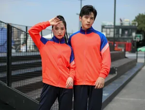 Couple portant des survêtements orange et bleu pour l'entraînement sportif en plein air