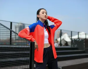 Détail d'une veste de sport orange et bleu vif sur un mannequin en extérieur.