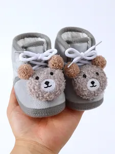 Close-up of grey plush baby winter boots with cute cartoon bear face design