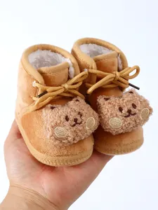 Warm plush fleece-lined baby winter boots featuring a cute brown bear design held in hand