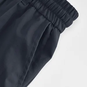 Detail view of the elastic waistband and side pocket on men's dark casual trousers