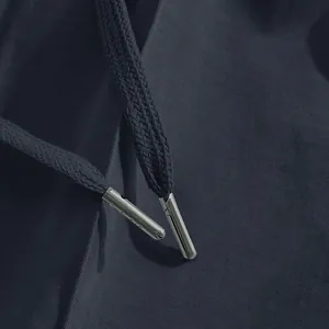 Macro detail shot of silver metal aglets on navy drawstring casual business pants for men