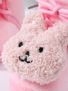 Close-up of cute plush rabbit design on warm pink baby winter floor shoes