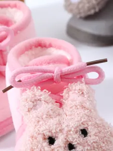 Close-up of pink plush baby winter shoes with soft bunny design and bow detail