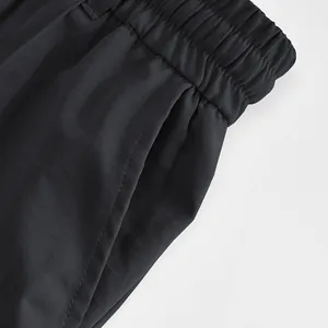 Close-up of men's black trousers showing elastic waistband and side pocket detail