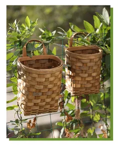 Paniers muraux en bois tissés suspendus à une clôture avec de vertes plantes grimpantes