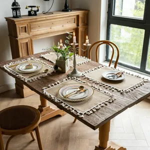 Rustic rectangular jute placemats with white tassel edges on a vintage wooden table detail.