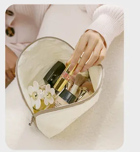 Nahaufnahme einer cremefarbenen Kosmetiktasche mit Make-up und Pinseln im Inneren