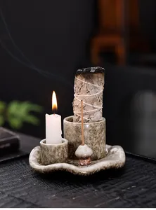 Detalle del portavelas de cerámica con forma de hongo, salvia blanca e incienso