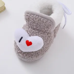 Detaillierte Makroaufnahme grauer Plüsch-Babystiefel mit Herzstickerei für Winter.