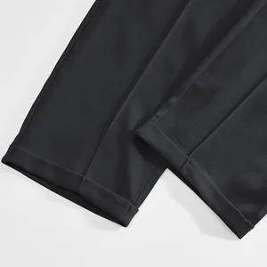 Close-up of cuffed leg openings on dark grey men's business casual trousers