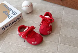Stylish red girls' German trainers featuring lace trim and bow embroidery details.
