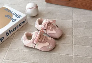 Detail shot of pink girls' bow sneakers featuring delicate lace trim and suede texture