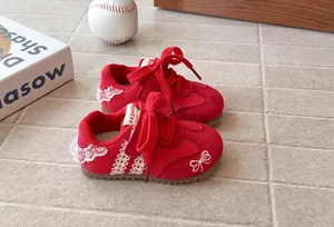 Close-up of red girls' GAT shoes featuring delicate lace trim and embroidered bows