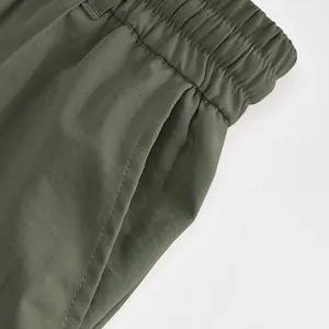 Close-up detail of army green men's trousers featuring elastic waist and side pocket