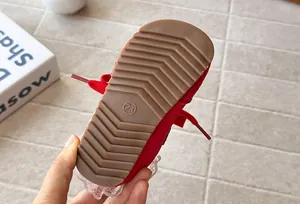 Close-up detail showing the anti-slip brown rubber sole of red girls' lace-up sneakers