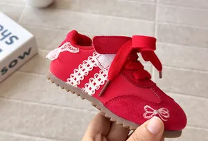 Close-up of red toddler sneakers with white lace trim and bow embroidery