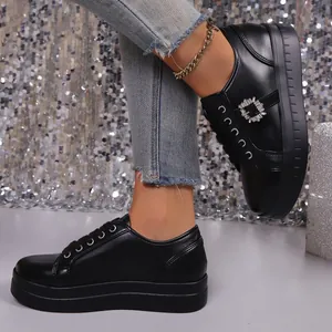 Gedetailleerd overzicht van zwarte glanzende plateau sneakers met elegante strass gesp.