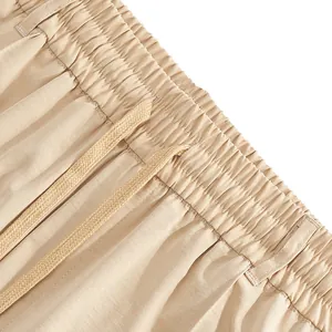Detail showing the elastic waistband and drawstring of men's beige casual trousers.