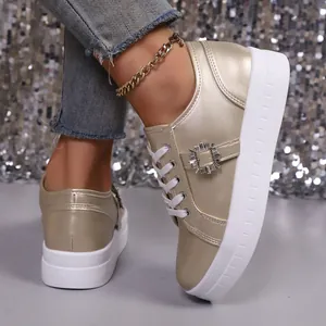 Close-up van gouden metallic plateau sneakers met een stijlvolle decoratieve strass-gesp