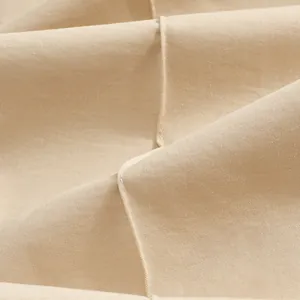 Macro detail of beige twill fabric with high-quality stitching on men's casual trousers.