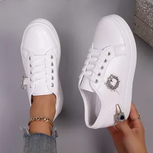 Gedetailleerde weergave van witte platform sneakers met kristallen gesp en dikke zolen