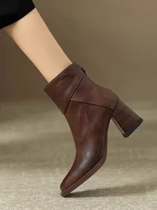 Detail view of brown vintage high-heeled ankle boot on foot with block heel.