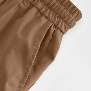 Close-up view of the elastic waistband and side pocket detail on men's brown casual trousers.