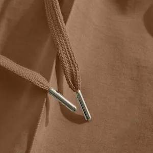 Close-up view of durable brown drawstring aglets on men's casual cotton chino pants.